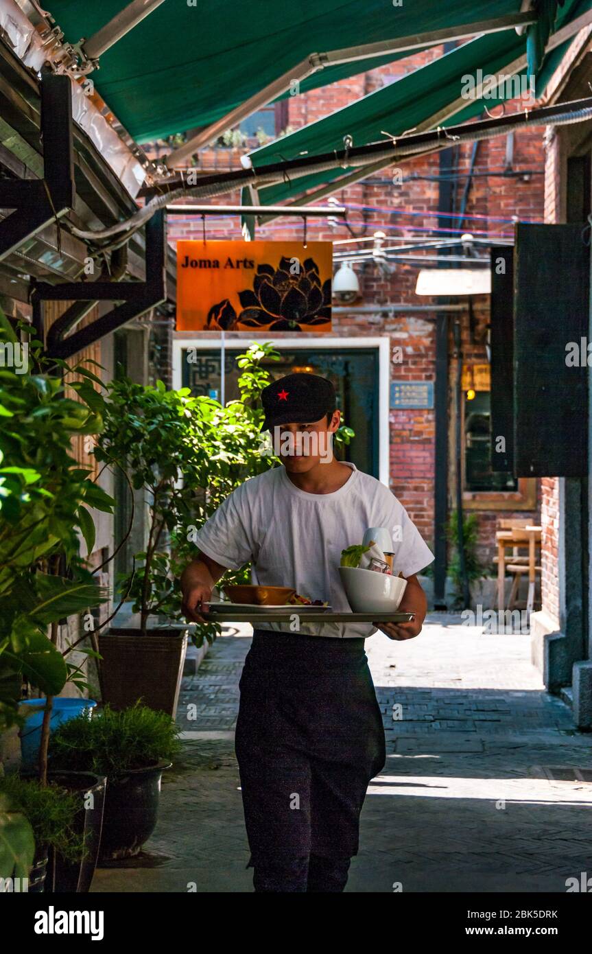 A waiter delivering a tray of food in the Tianzifang area of Shanghai, China. Stock Photo
