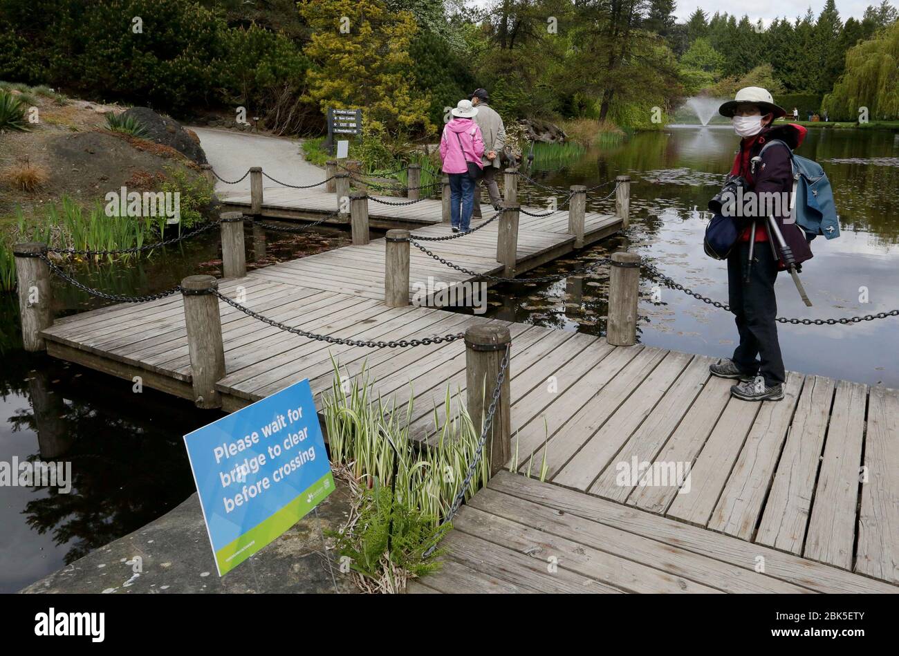 Vancouver, Canada. 1st May, 2020. A visitor follows the sign instruction by waiting the bridge to be cleared before crossing it at the reopened VanDusen Botanical Garden in Vancouver, Canada, on May 1, 2020. Vancouver started on Friday to gradually reopen public recreation facilities with safety measures amid COVID-9 pandemic. Credit: Liang Sen/Xinhua/Alamy Live News Stock Photo