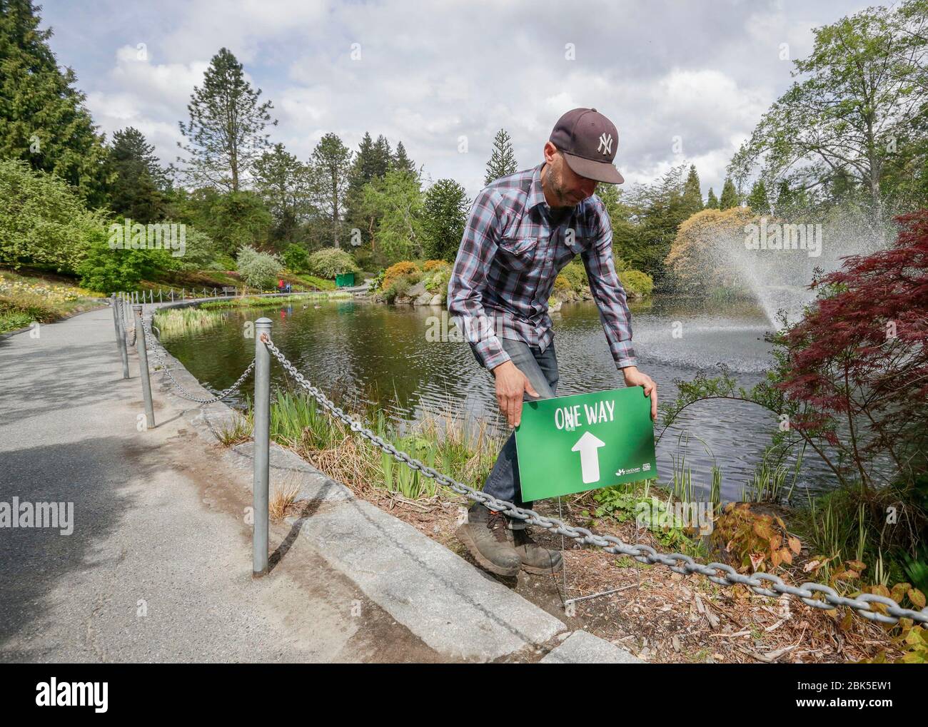 Vancouver, Canada. 1st May, 2020. A staff member puts a one-way sign at the reopened VanDusen Botanical Garden in Vancouver, Canada, on May 1, 2020. Vancouver started on Friday to gradually reopen public recreation facilities with safety measures amid COVID-9 pandemic. Credit: Liang Sen/Xinhua/Alamy Live News Stock Photo