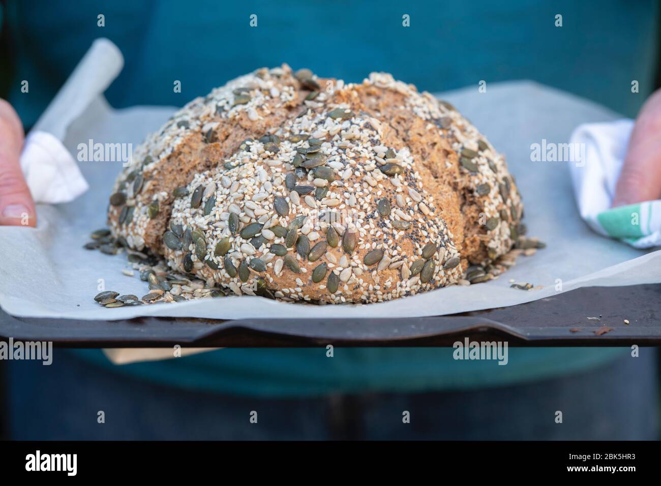 Man holding a loaf of Homemade soda spelt bread on a baking tray Stock Photo