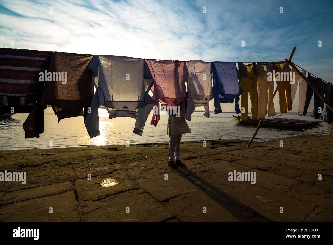 Laundry boy makes his clothes dry on the bank of river Ganges at Varanasi ghat in Uttar Pradesh, India. Stock Photo