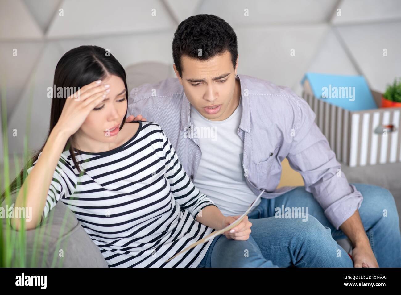 Unpleasantly surprised husband and wife reading a document Stoc