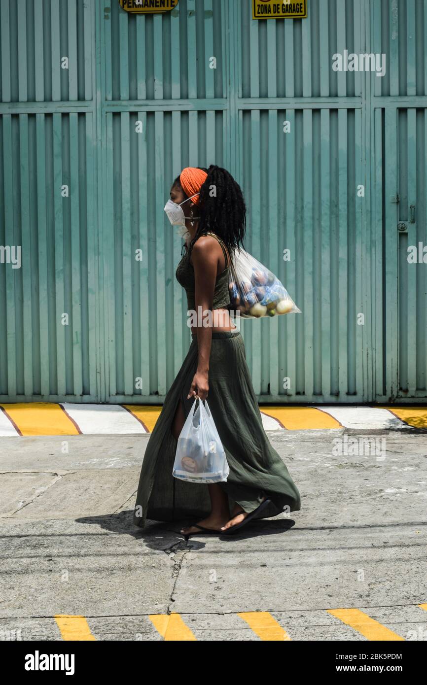 Young woman carrying grocery bags in empty city during Coronavirus lockdown in Colombia Stock Photo