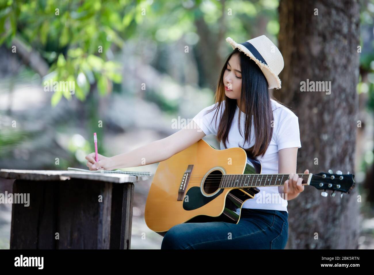 Portrait of beautiful girl playing the guitar with writing at nature  background Stock Photo - Alamy
