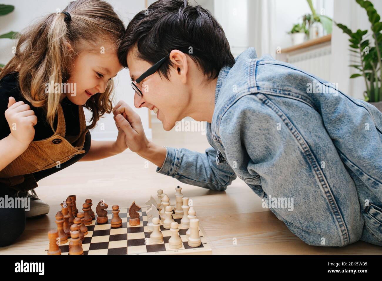Friendly competition concept. dad and dau playing chess and batting heads Stock Photo