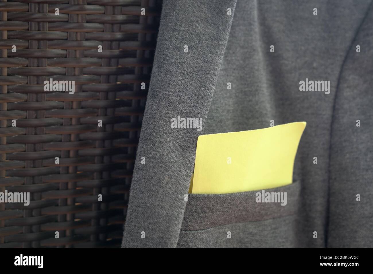 Blank yellow paper stuck out from pocket of grey jacket. Space for text. Stock Photo
