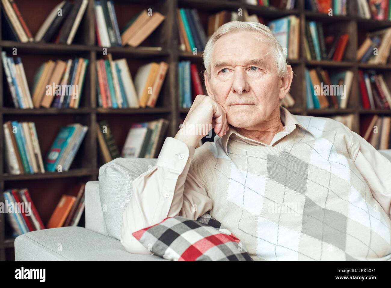 Senior man alone sitting at library thoughtful Stock Photo