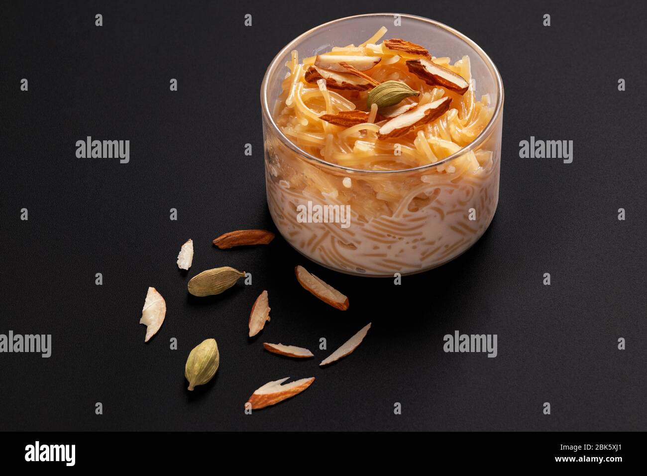 Vermicelli dessert, popular sweet dish know a kheer made with milk and garnish with dry fruits isolated on dark gray background, served in glass bowl. Stock Photo