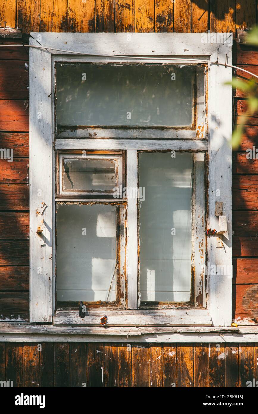 An old wooden white window in a country house. The paint was old and peeling Stock Photo