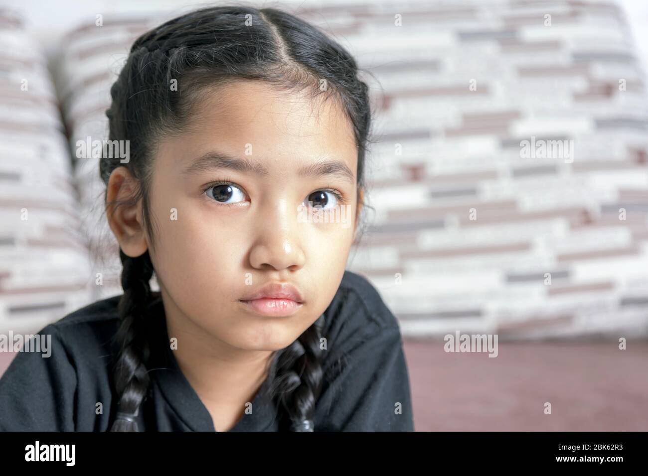 Close-up A little Asian girl in a black braid on the sofa Stock Photo