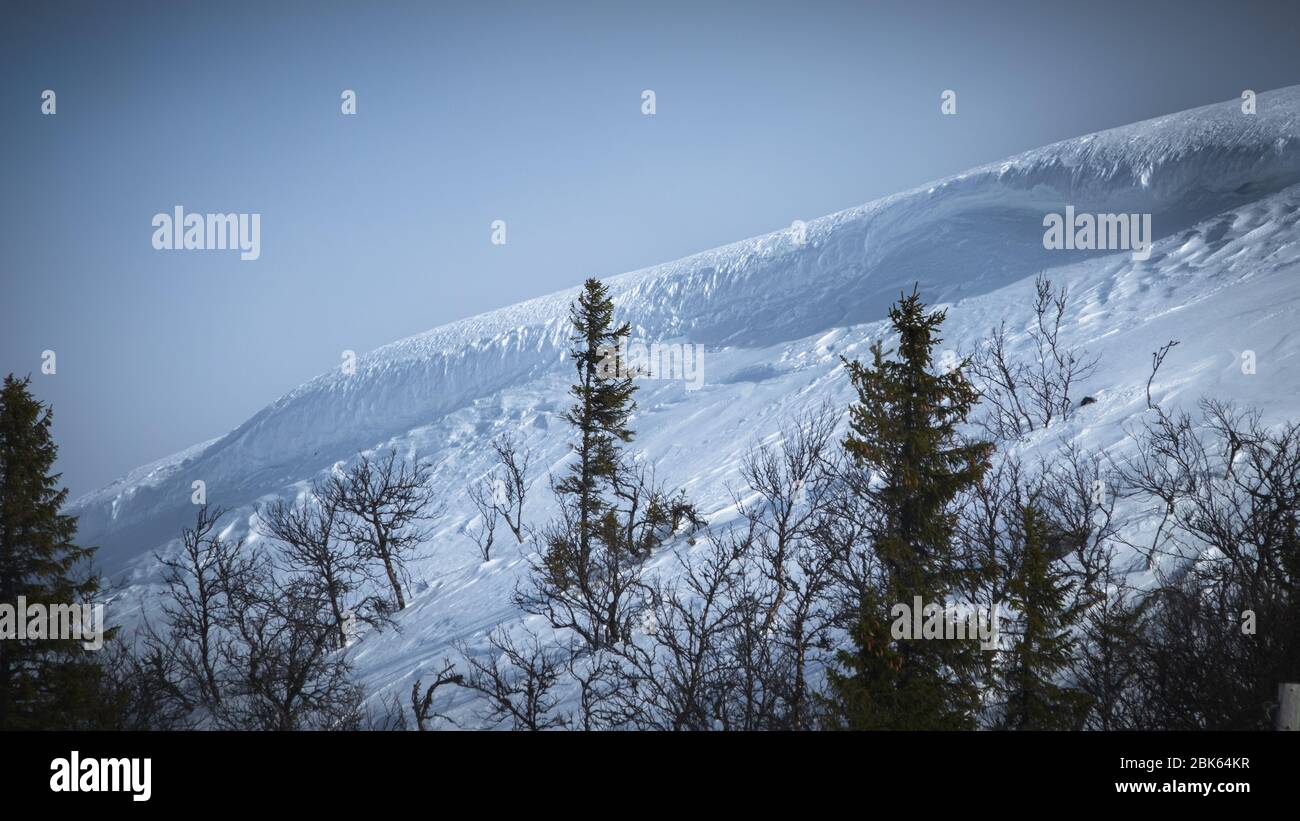 Avalanche risk zone. Landscape with dramatic cliff side on snowy mountain. Stock Photo
