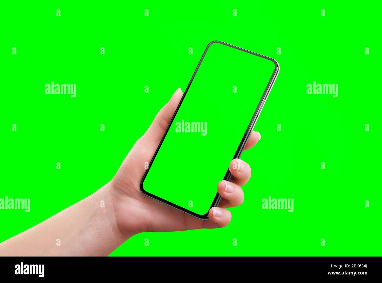 Phone mockup isolated in chroma key green. Soft retouched woman hand holds the phone. Close-up Stock Photo