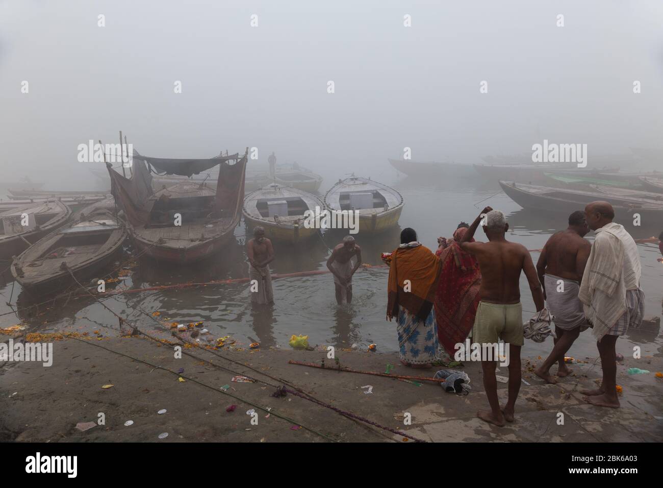 People taking bath on a foggy morning in the river Ganges near Varanasi, India. It's their belief, taking bath in Ganges washing their all sins. Stock Photo