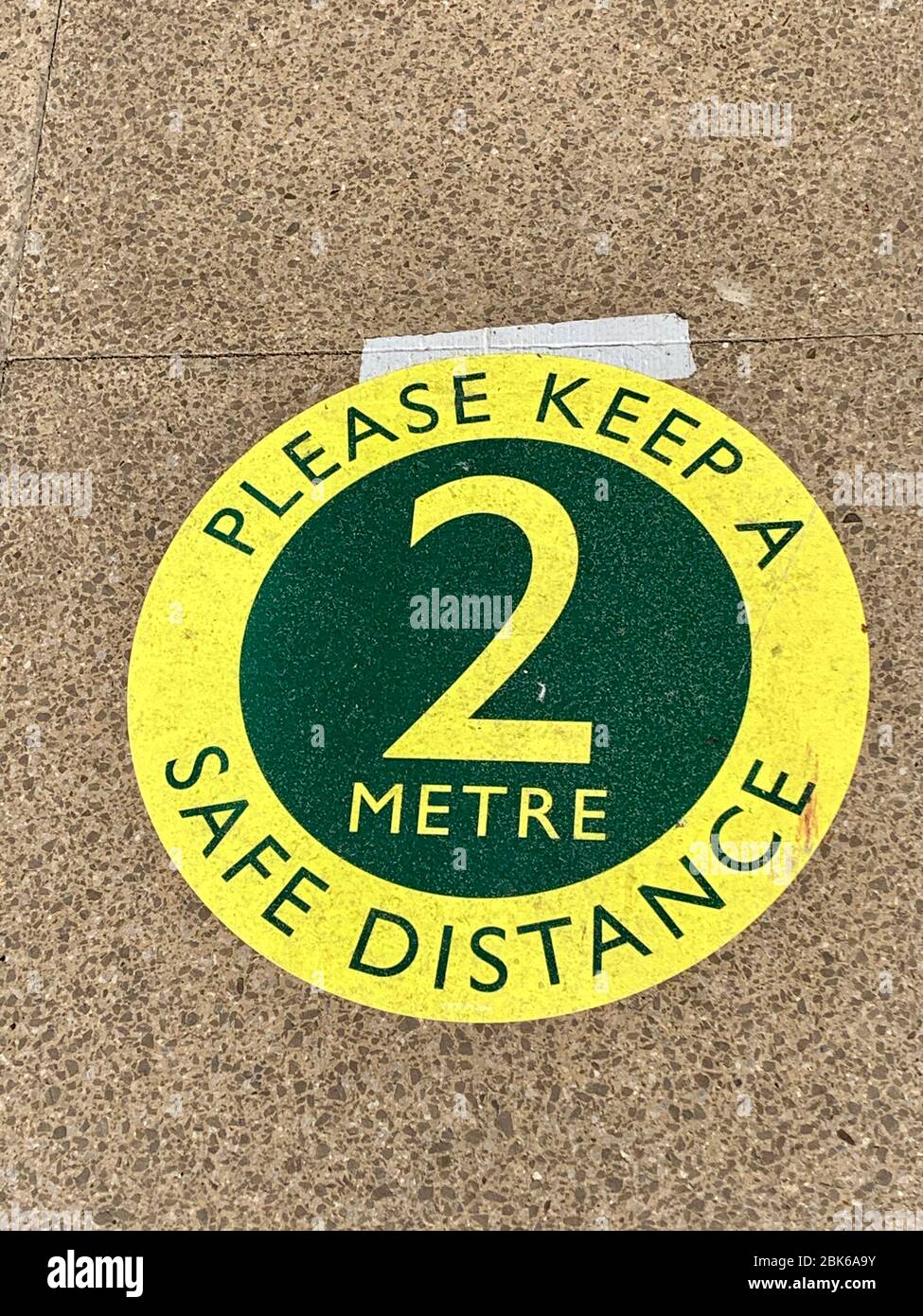 Please Keep a Safe Distance - 2 Metre - sign on floor outside Waitrose Supermarket in response to covid-19 coronavirus pandemic Stock Photo