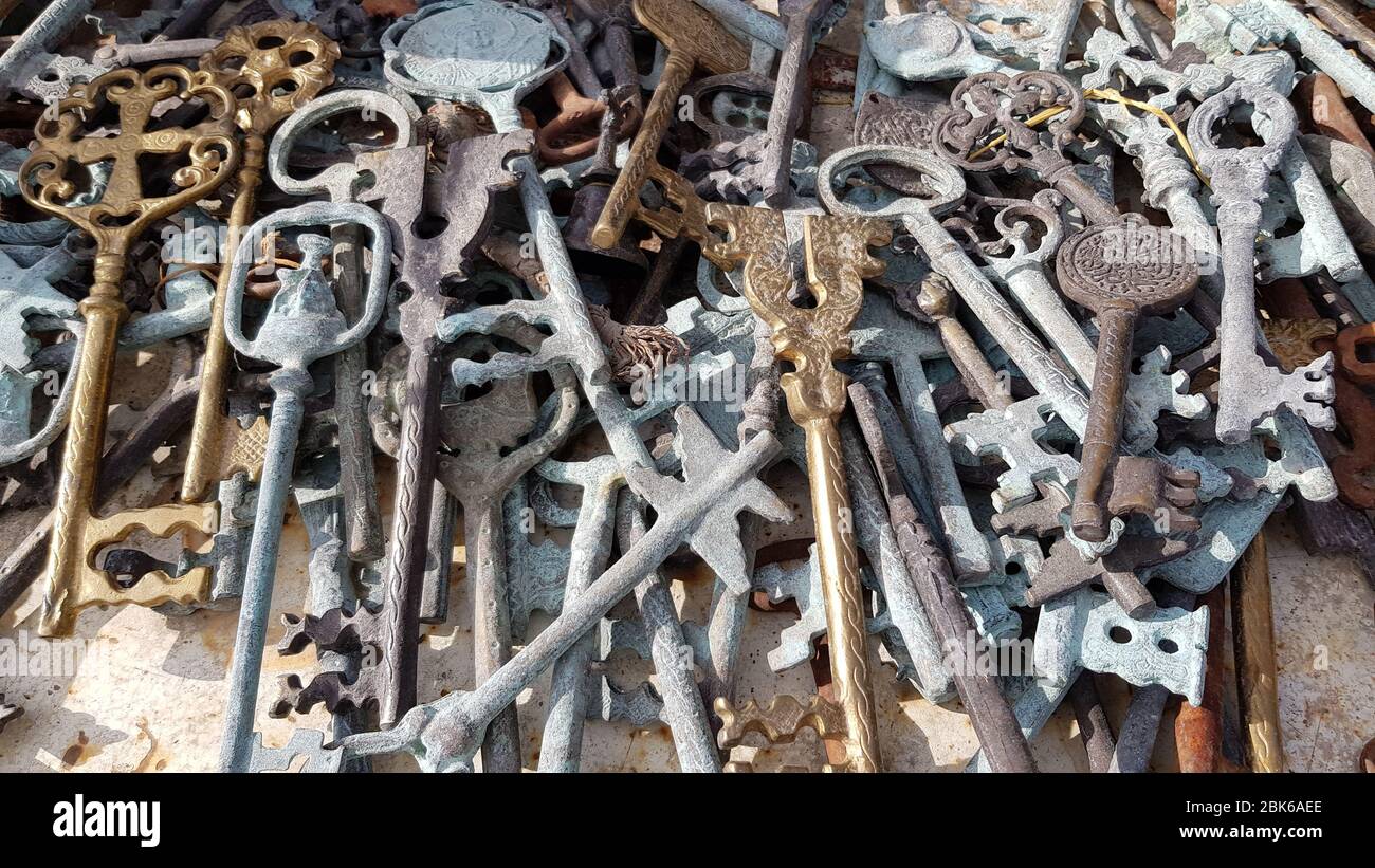 Different vintage keys made by metal casting from yellow, brown and gray metal. Antique ornate keys with whimsical sculptural handles. Mess heap of va Stock Photo