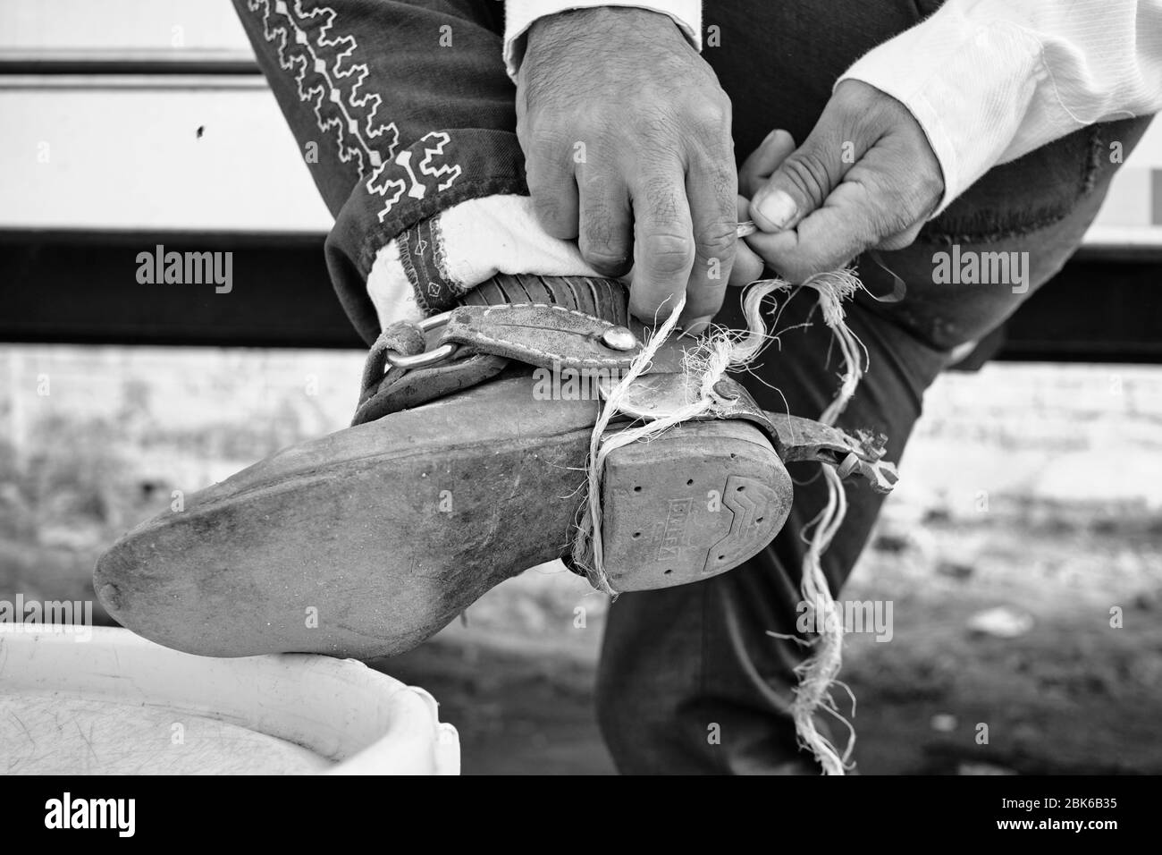 Mexican cowboy tying his spurs with a rope. Stock Photo