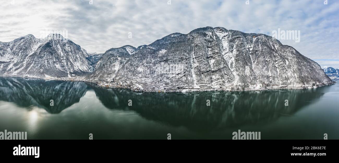 Aerial panoramic drone view of Hallstatt lake surrounded by snow Stock Photo