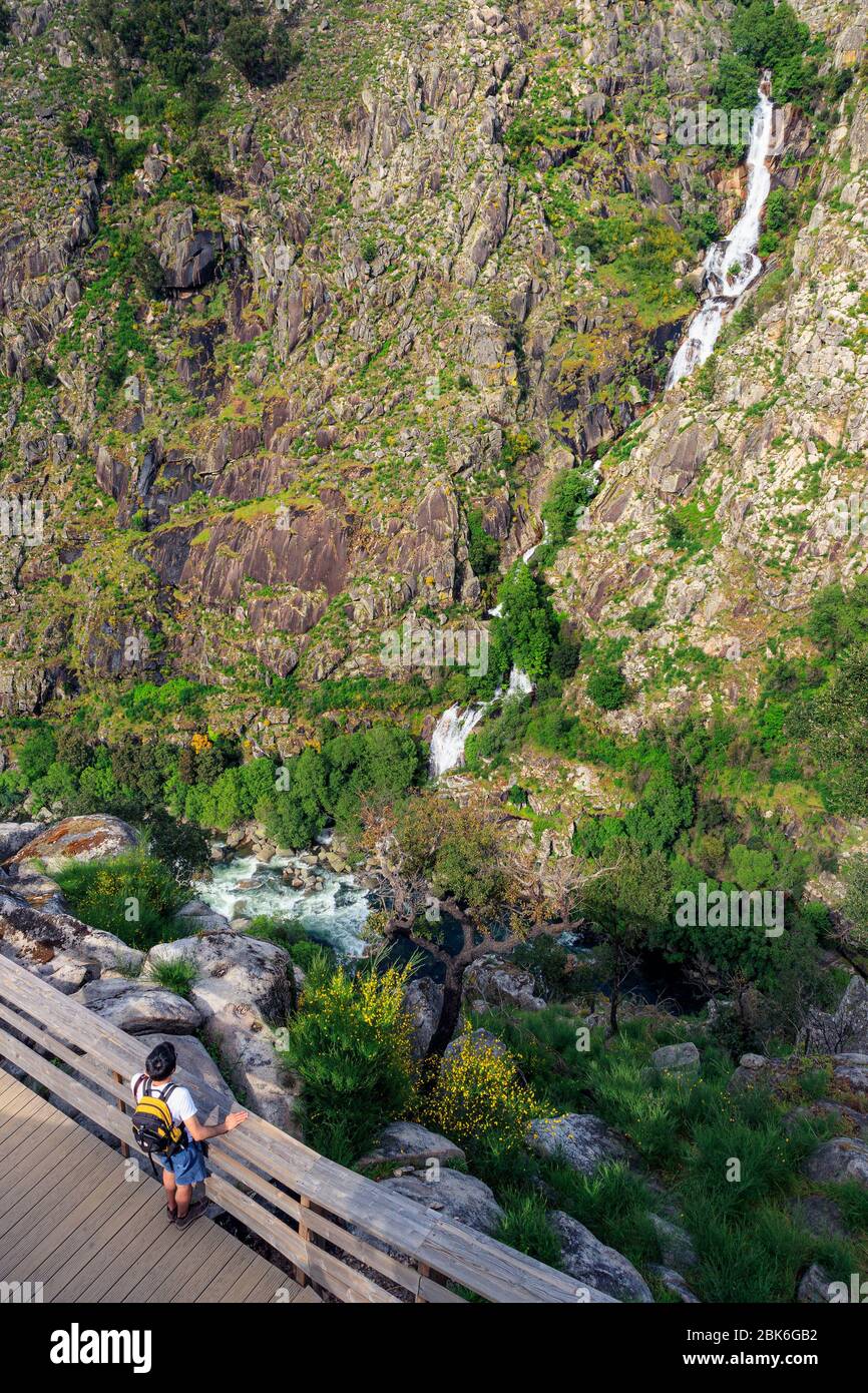 Arouca, Portugal - April 28, 2019: Young backpacker tourist contemplating the Paiva river and the Aguieiras waterfall on the Paiva walkways, near Arou Stock Photo