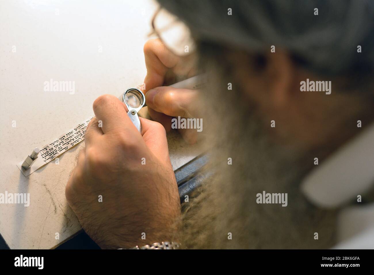 An orthodox rabbi and scribe corrects the Hebrew lettering on a ...