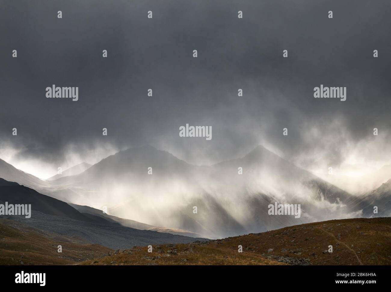 Landscape of Tian Shan Mountains at dark dramatic stormy sky at sunset in Kazakhstan Stock Photo