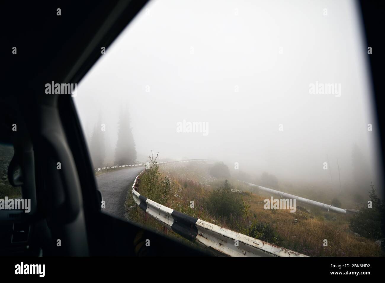 View of foggy mountain road with forest from the car window Stock Photo