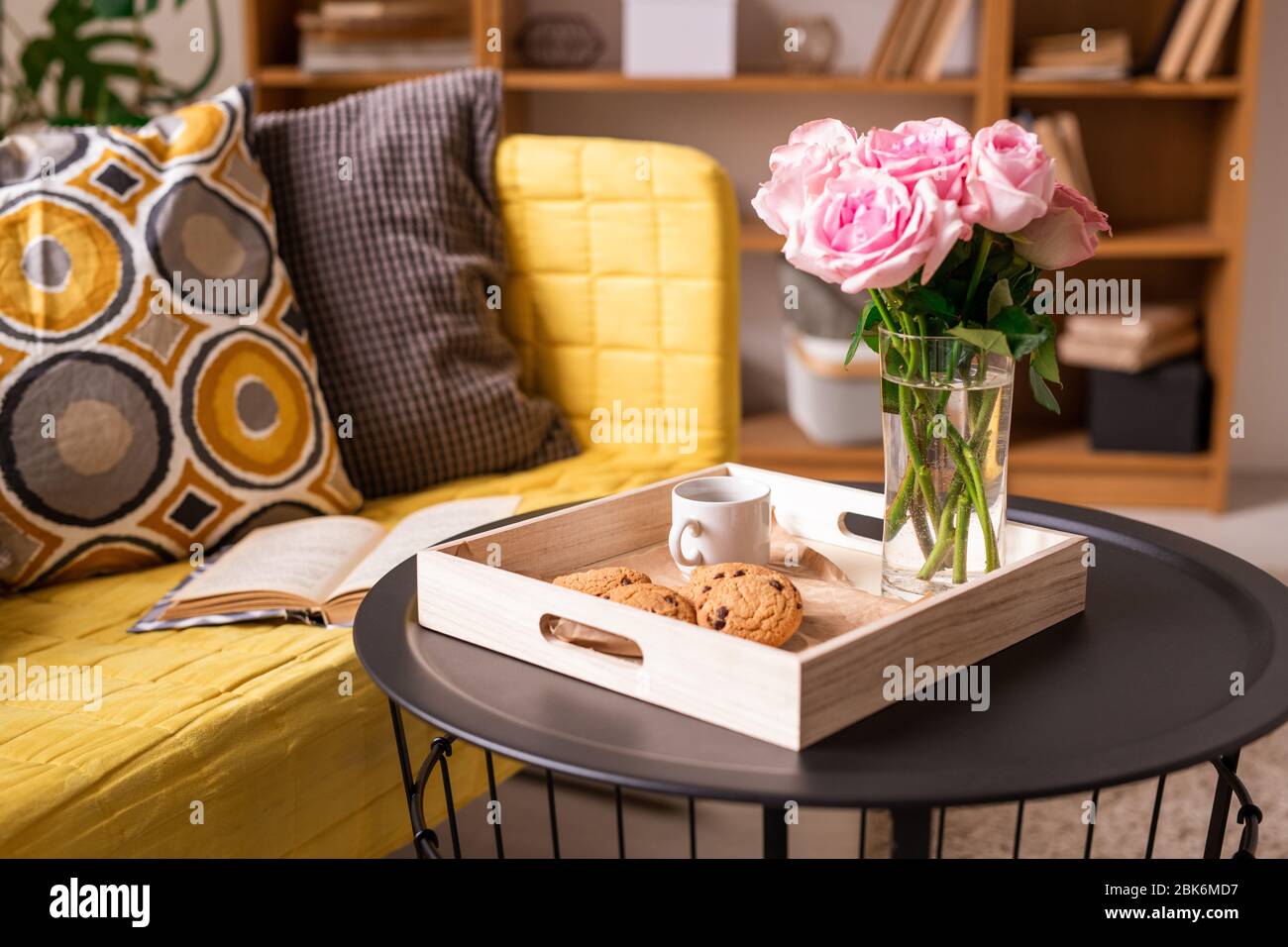 Home Interior With Pillows And Open Book On Couch And Small Table With Cookies Cup Of Coffee And Bunch Of Pink Roses In Wooden Box Stock Photo Alamy