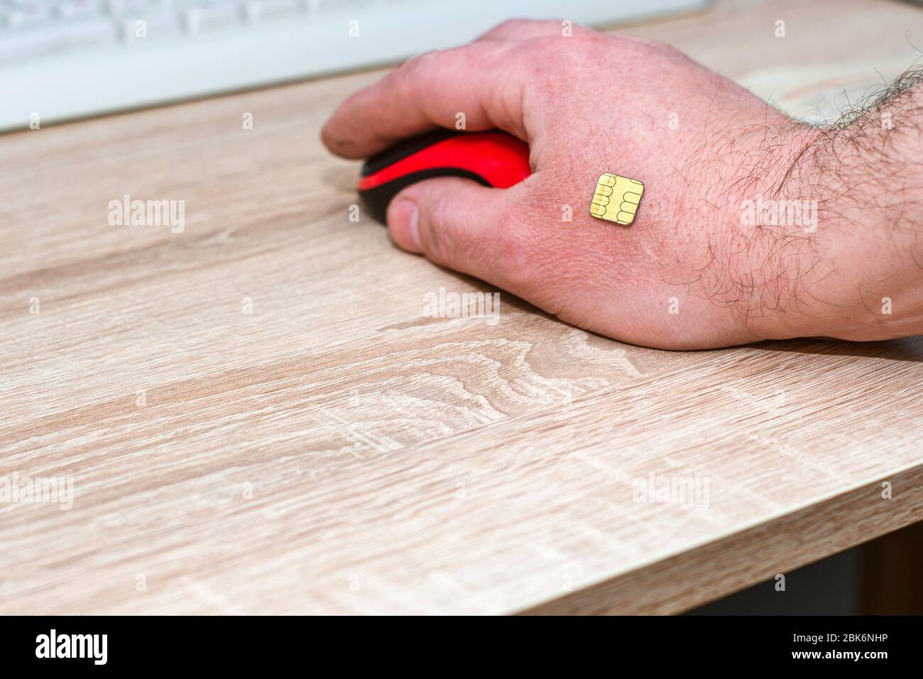 concept chipization of the population a man works at a computer a microchip is implanted in his hand Stock Photo