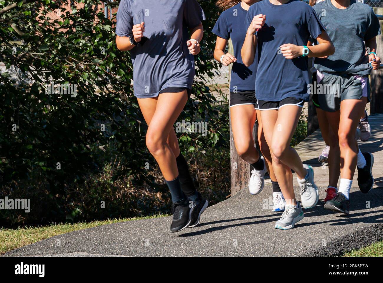 A group of teenage girls running together during cross country practice ...