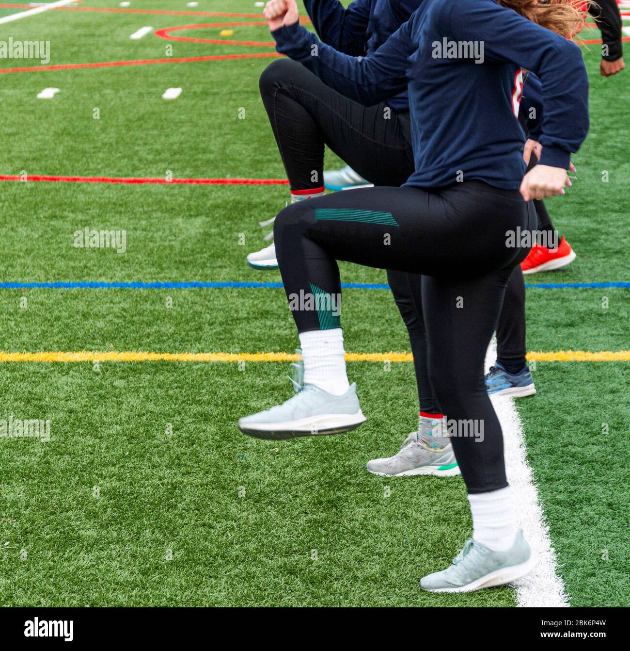 A high school girls track and field team practicing askip drills on a