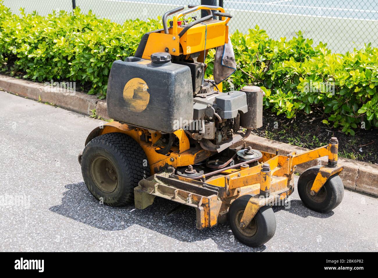 A yellow, professional landscaping lawnmower in a parking lot. Stock Photo