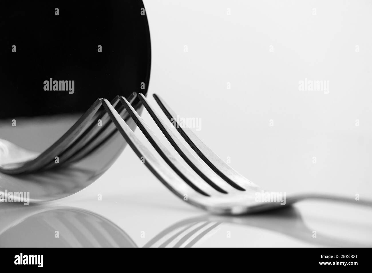 luxury metal fork for food elegant dinner still life reflection on round mirror black and white classic background Stock Photo