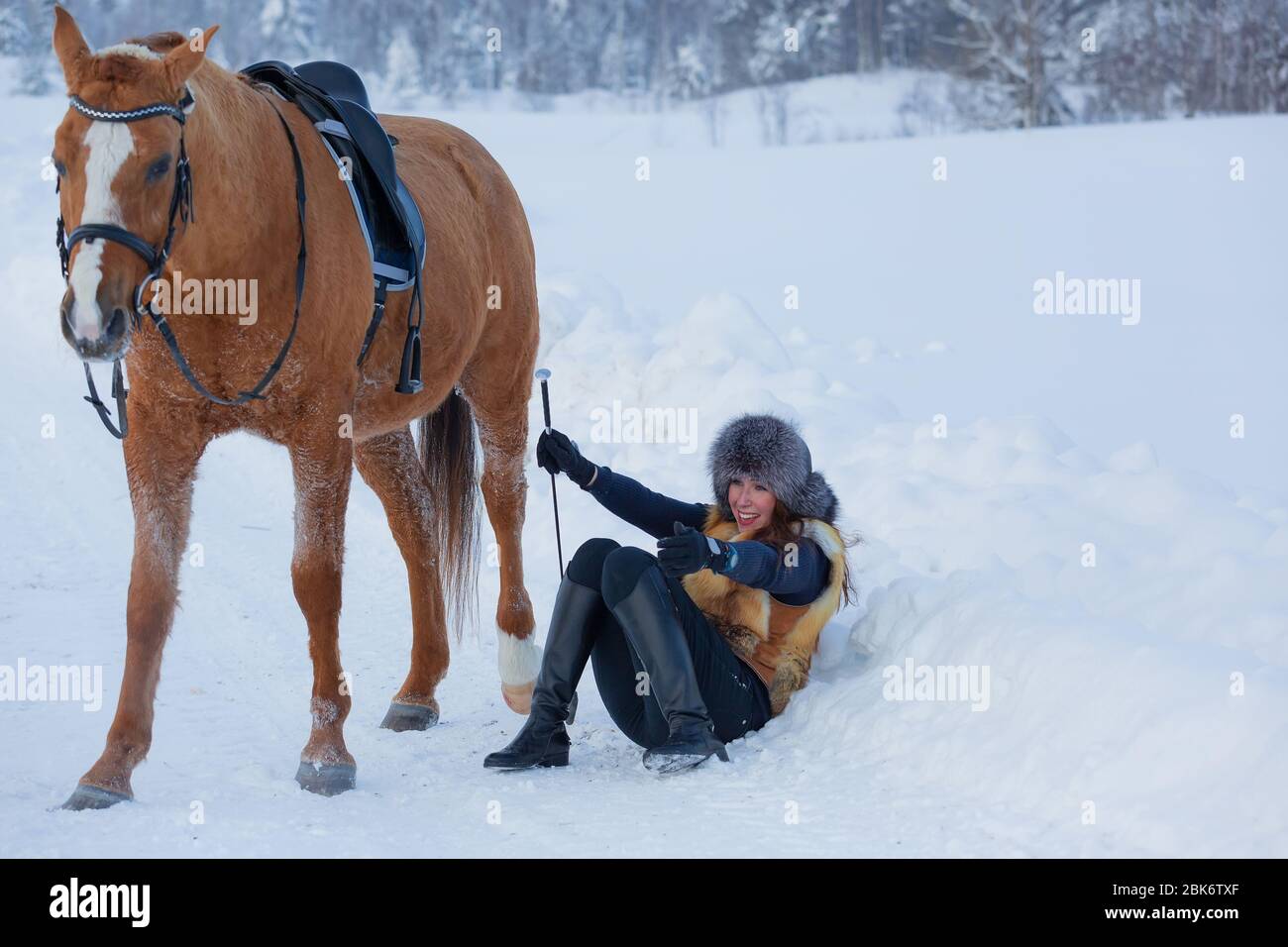 Young woman fell in the snow and she laughs Stock Photo