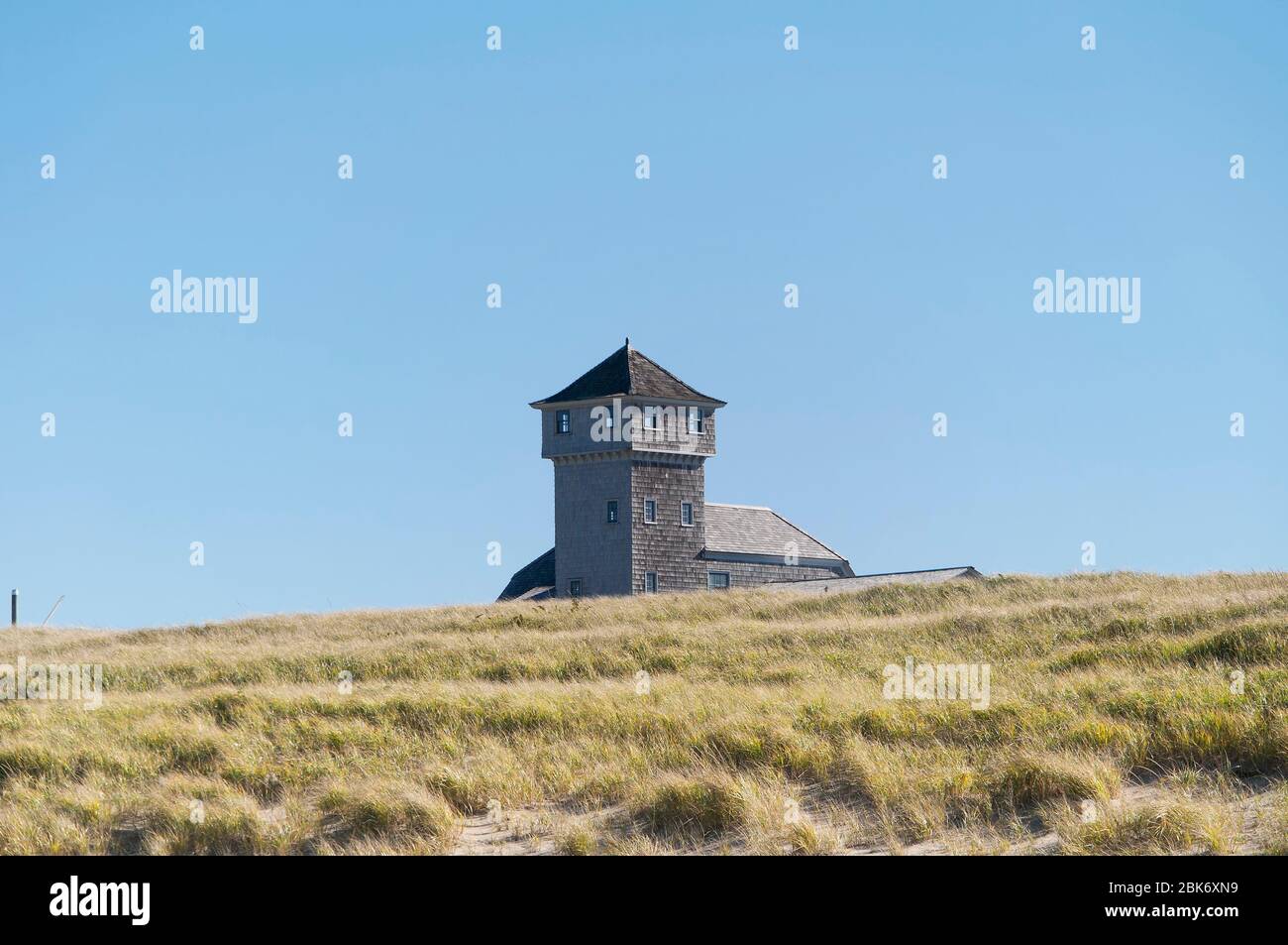 The tower and exterior of the old harbor life saving station rising above the grass covered dunes on the national seashore at race point in provinceto Stock Photo