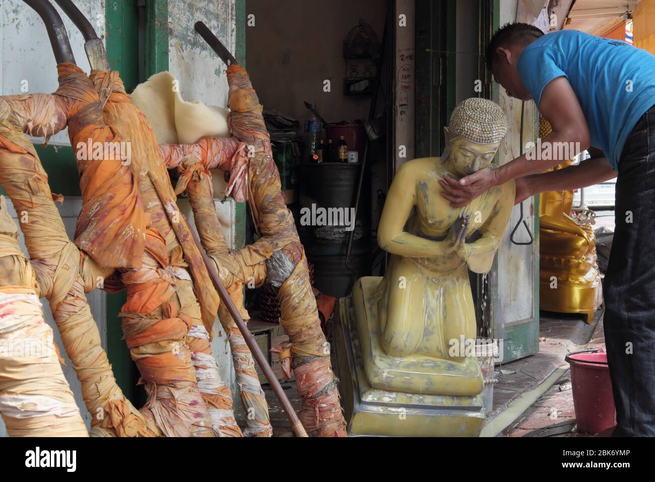 At a factory for Buddha statues in Bamrung Muang Road, Sao-Ching-Chaa, Bangkok, Thailand, an employee carefully moves a yet unfinished Buddha statue Stock Photo