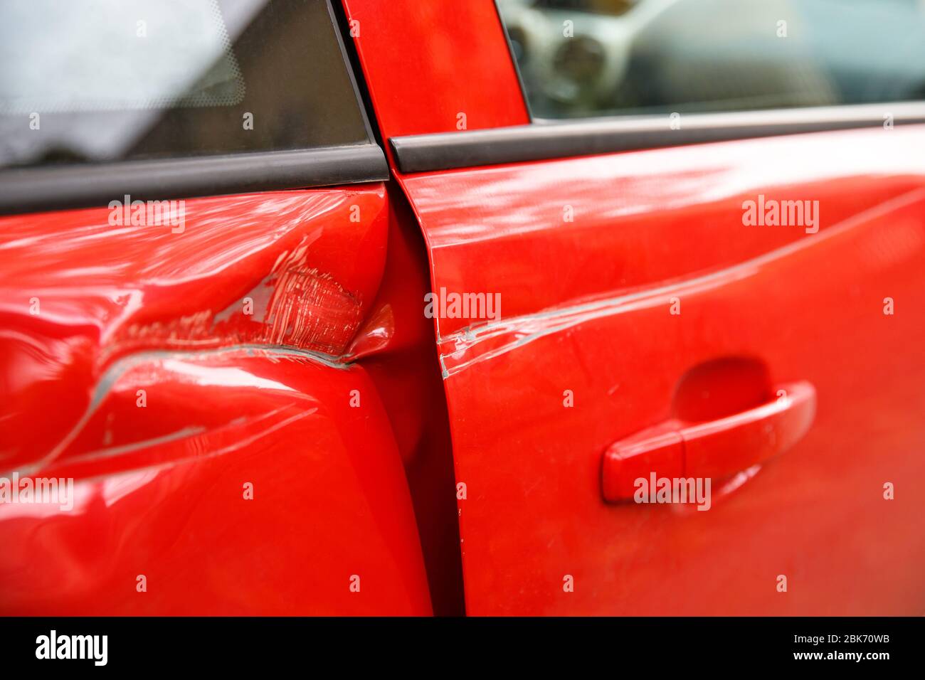 Door red car damaged in a deep dent accident, scratches on the doors. Car repair concept. Stock Photo
