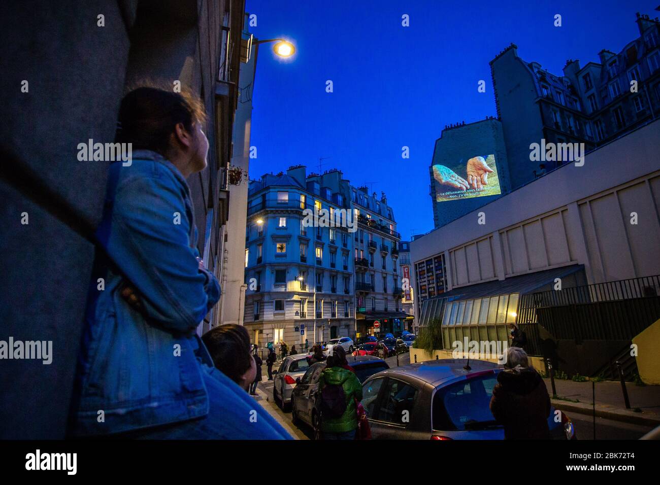 Paris, France. 1st May, 2020. Residents watch a film screened on the wall at the rue Daubenton in Paris, France, May 1, 2020. Every Friday evening, the independent cinema La Clef in the 5th arrondissement in Paris screens a film on a wall in the rue Daubenton for the inhabitants of the neighbourhood, during a strict lockdown to stop the spread of COVID-19. Credit: Aurelien Morissard/Xinhua/Alamy Live News Stock Photo