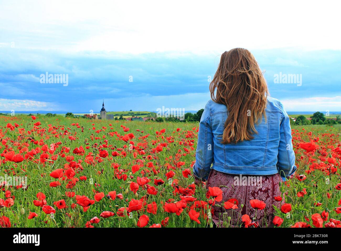 Girl standing in the field of poppies Stock Photo
