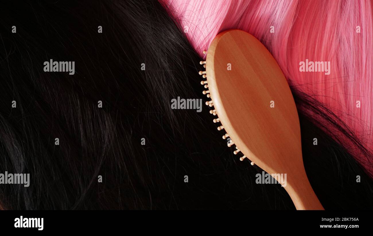 Pink and black wig with long hair and combs a wooden comb. Hairdresser and hair care Stock Photo