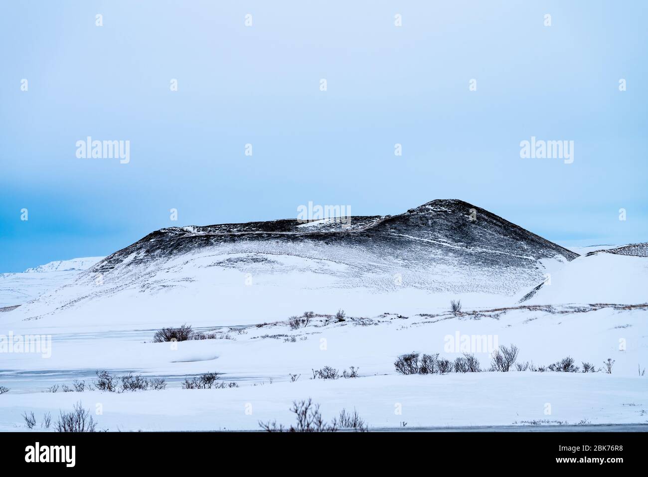 Single dramatic symetrical volcanic,snow covered crater near lake Myvatn, Iceland in mid winter, against a blue sky Stock Photo