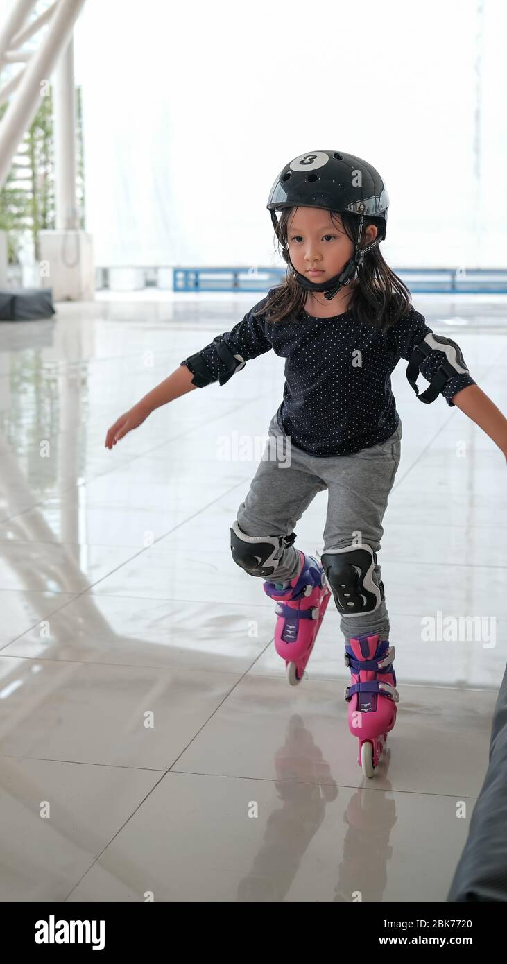 Cute Asian girl child learning how to keep balance on roller skate