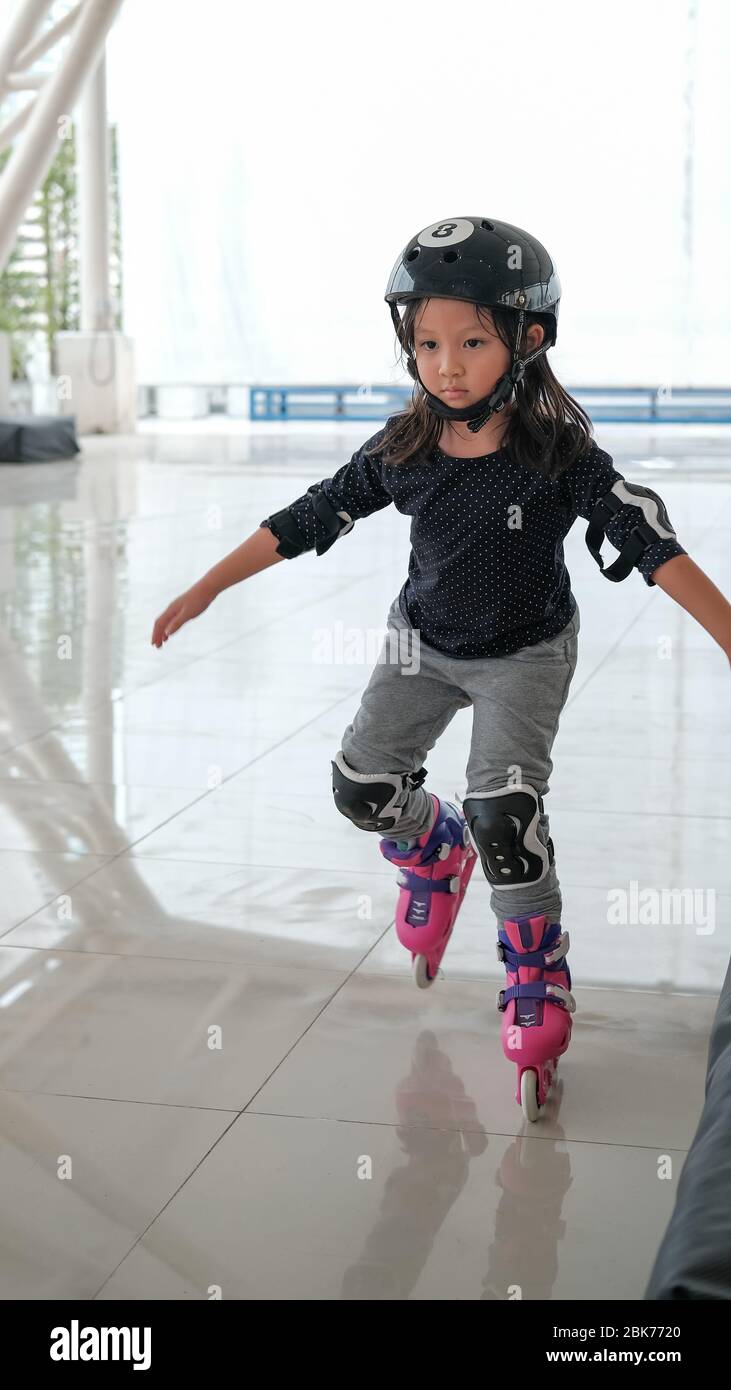 Cute Asian girl child learning how to keep balance on roller skate. Sport  outdoor activity for kid Stock Photo - Alamy