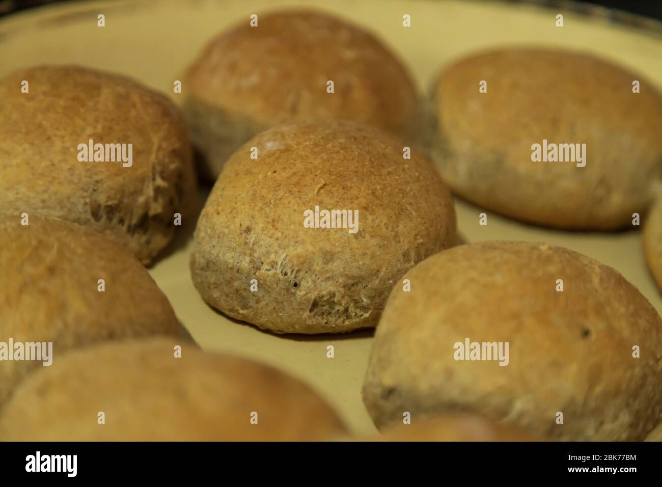 freshly baked wheat bread rolls one the center of focus the rest out of focus Stock Photo