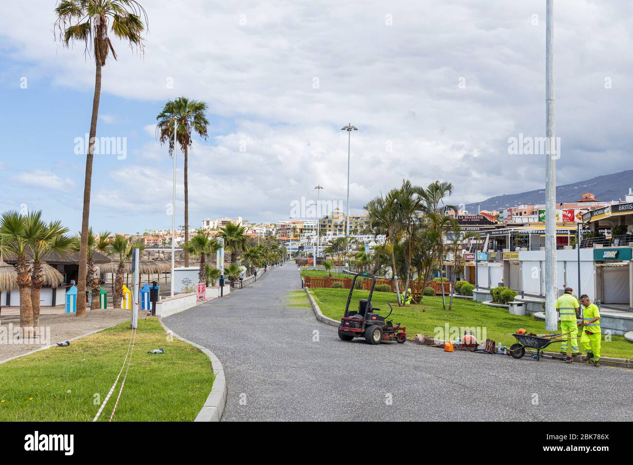 Gardeners continue maintaining the grass and plants along the promenade at Fanabe during the covid 19 lockdown in the tourist resort area of Costa Ade Stock Photo