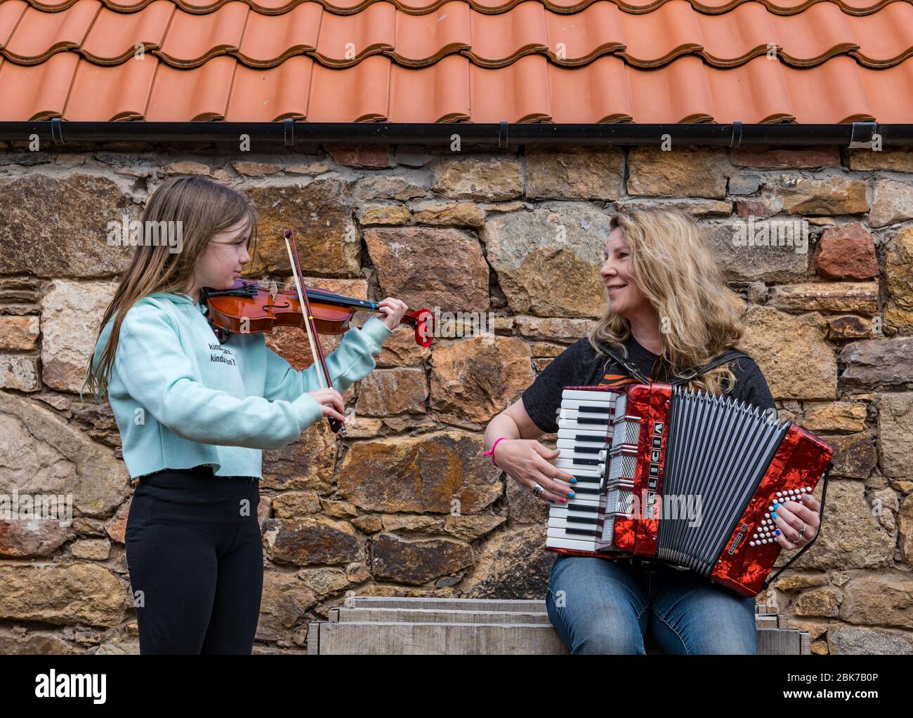 Camptoun, East Lothian, Scotland, United Kingdom. 2nd May, 2020. A community in lockdown: residents in a small rural community show what life in lockdown is like for them. Pictured: Ava, aged 10 years, and her mother, Harley, a musician, play the fiddle and accordion in the tune 'Somewhere Over the Rainbow' Stock Photo