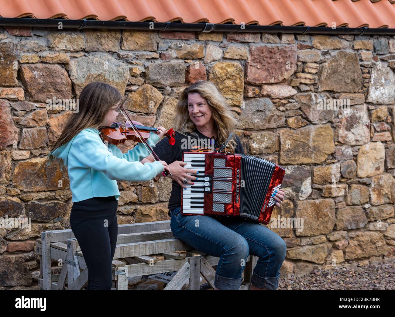 Camptoun, East Lothian, Scotland, United Kingdom. 2nd May, 2020. A community in lockdown: residents in a small rural community show what life in lockdown is like for them. Pictured: Ava, aged 10 years, and her mother, Harley, a musician, play the fiddle and accordion in the tune 'Somewhere Over the Rainbow' Stock Photo