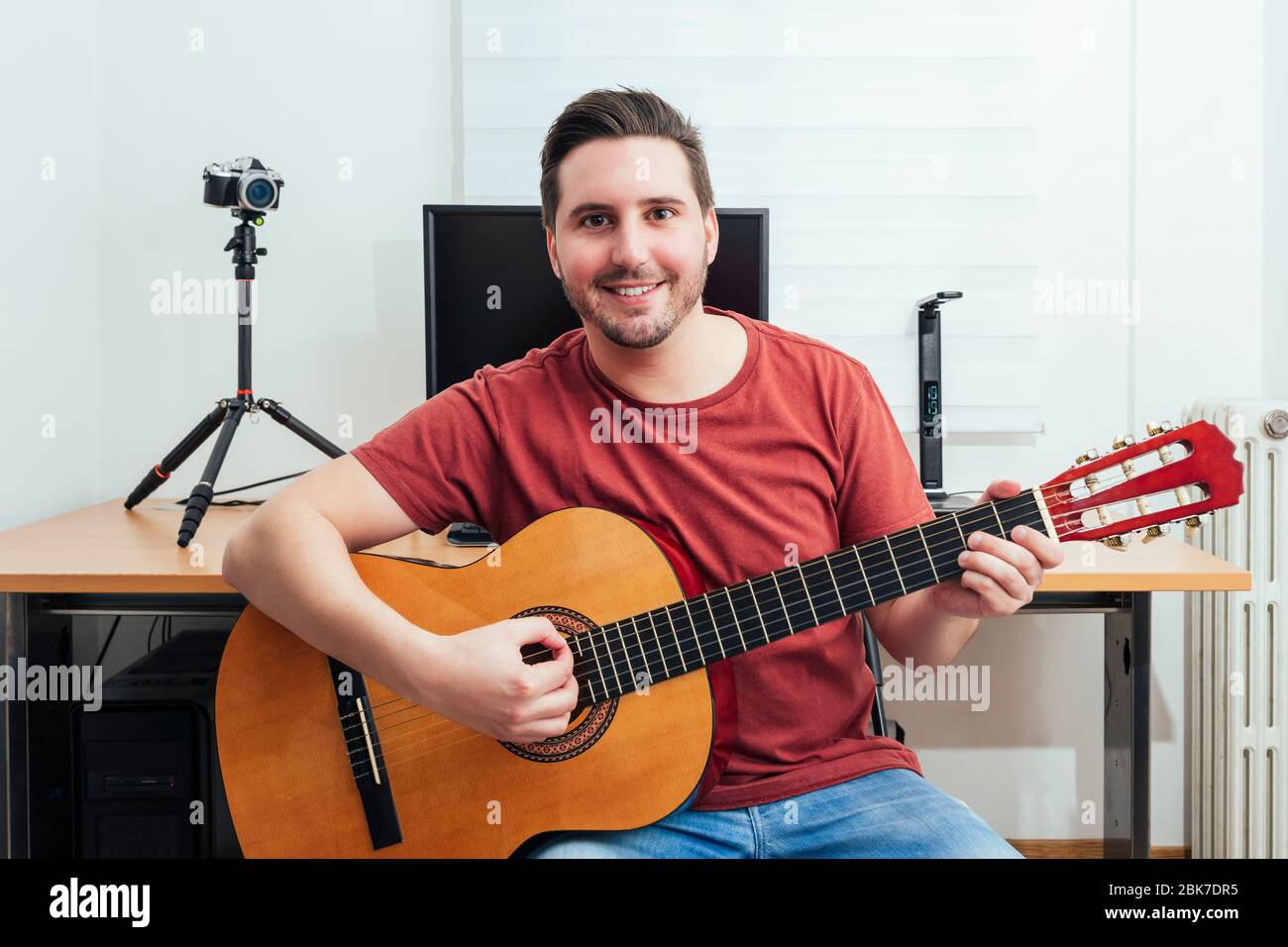Portrait of a blogger playing guitar from his home recording studio. Learning online concept. Stock Photo