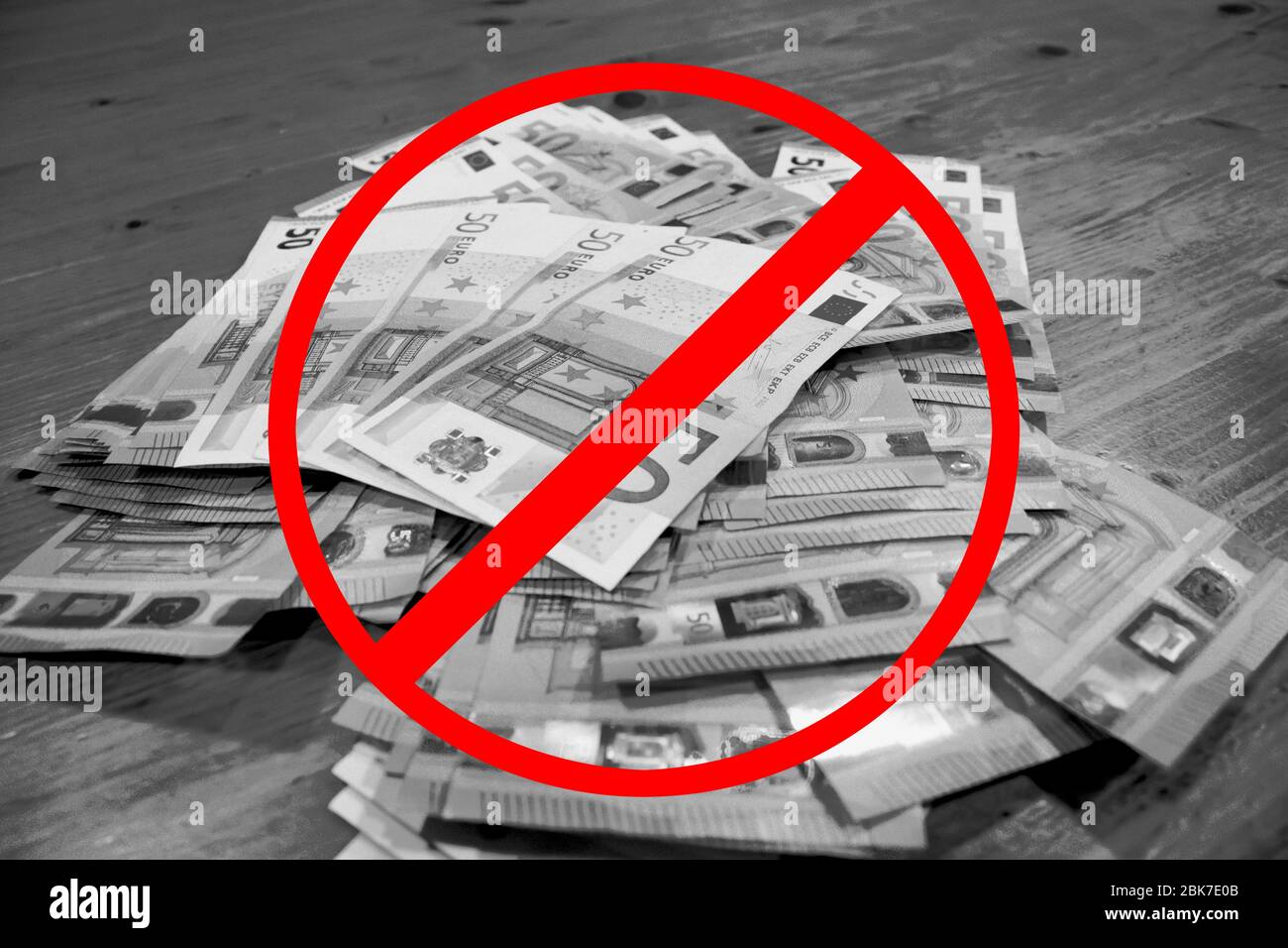 A pile of 50 euro banknotes laying on a wooden table. Black and white with a red ban sign. Unemployment and corruption after covid concept Stock Photo