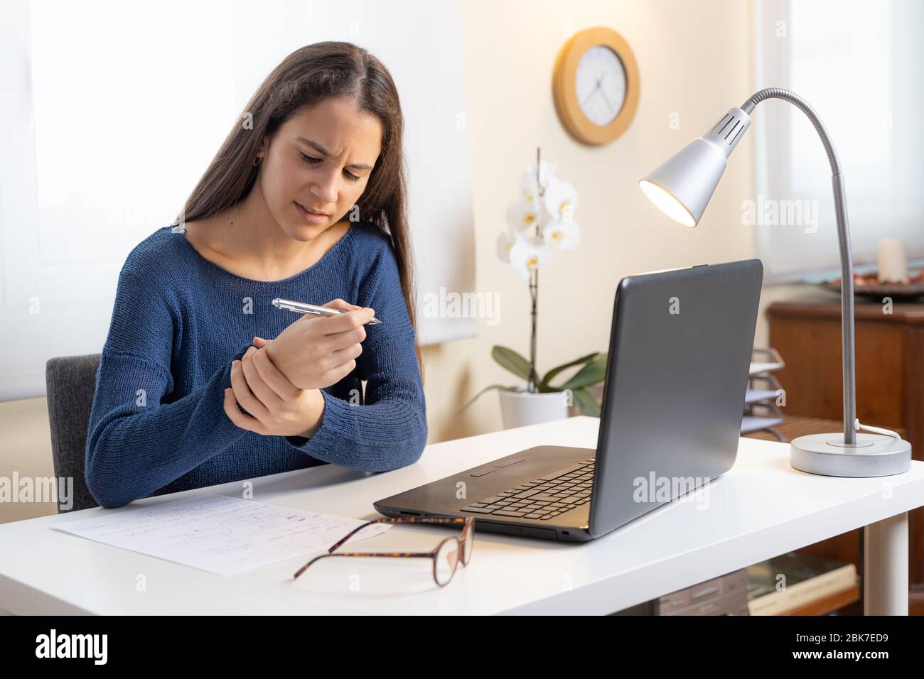 Teen girl with computer at home complaining of wrist pain Stock Photo