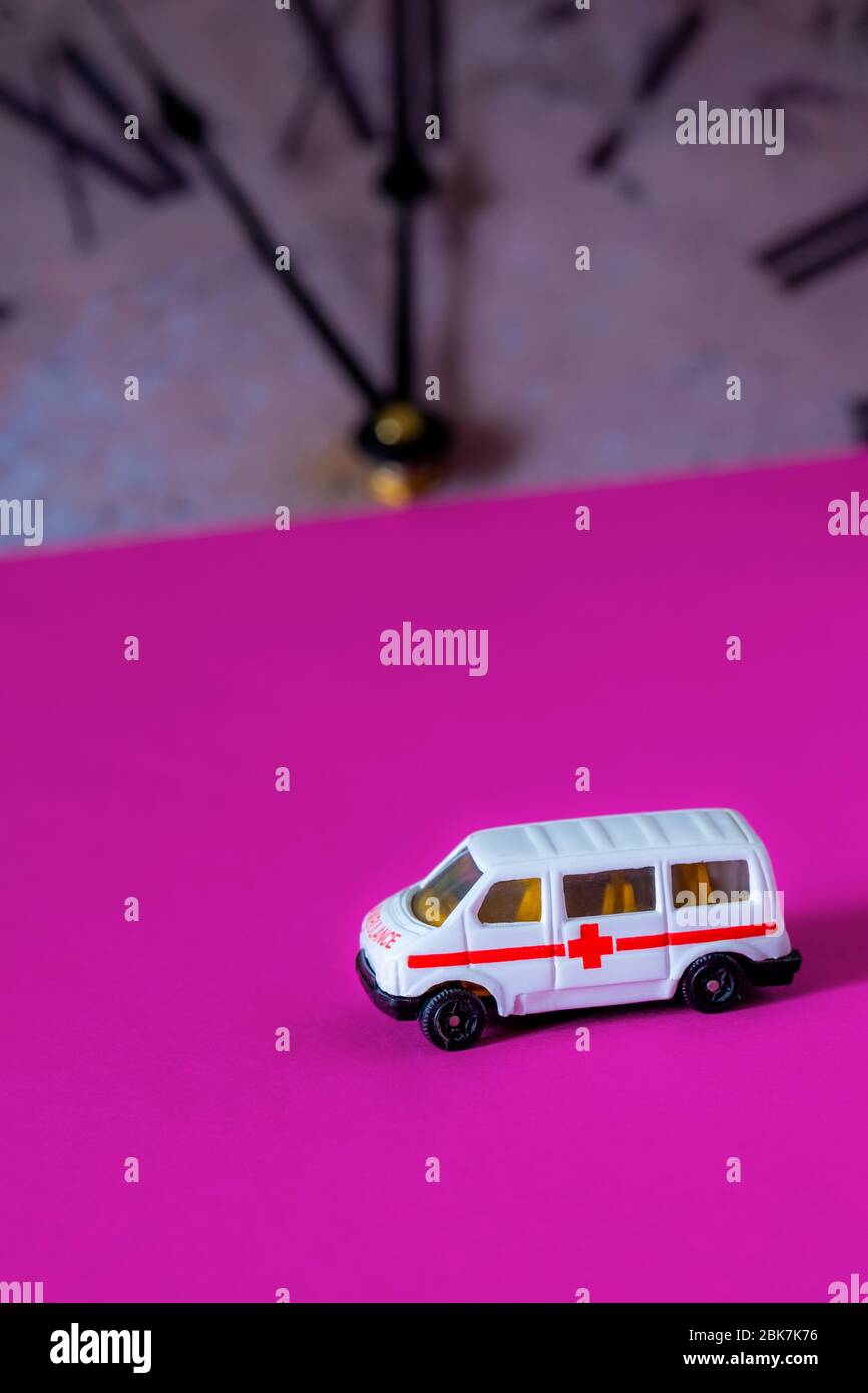 Toy ambulance car and old vintage watch on pink background. Concept time over. Stock Photo