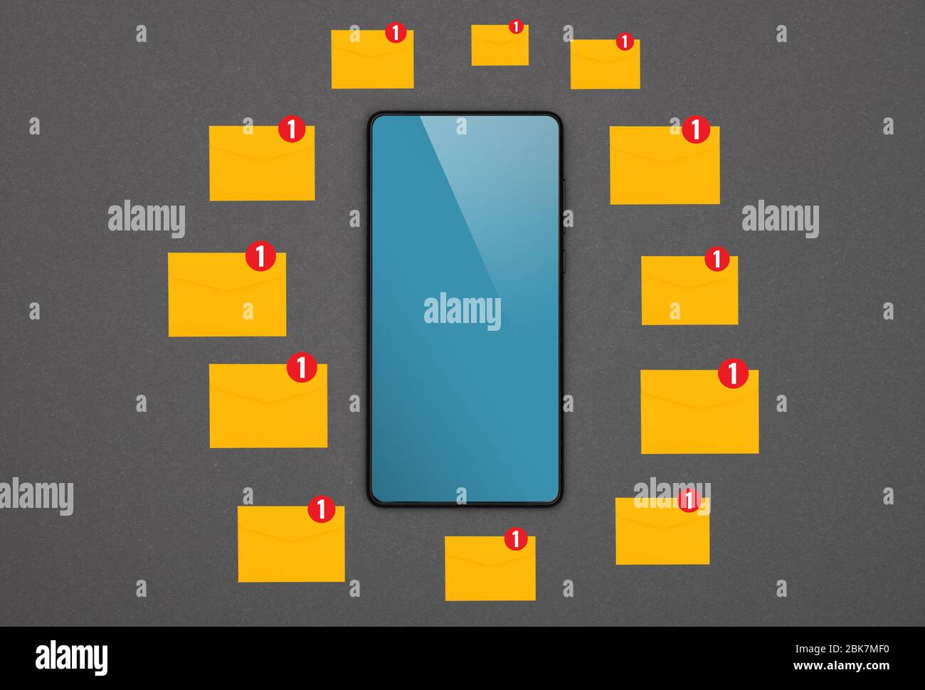 Close up one black smartphone with blank blue screen and many yellow envelopes of new messages over grey paper background, flat lay, directly above Stock Photo